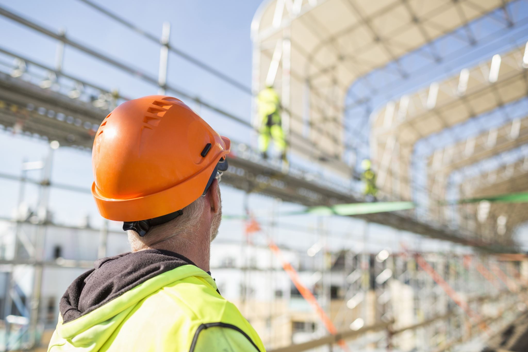 Worker-with-protective-gear-looking-up-at-construction-site